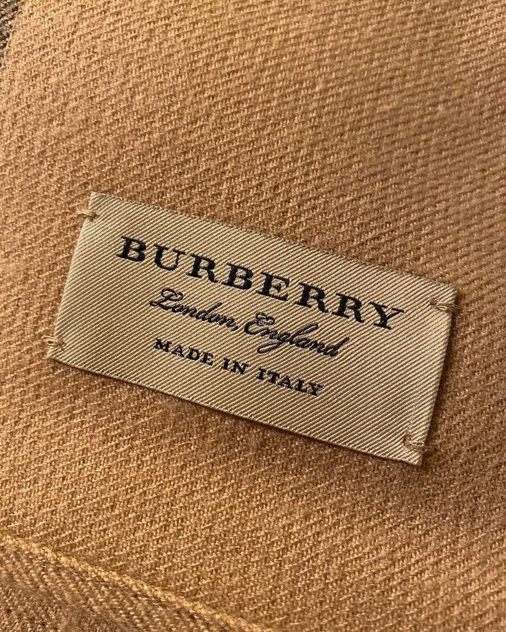 Athena Burberry zipper showing a metallic zipper with branded pull tab and fabric surrounding it in a close-up view.